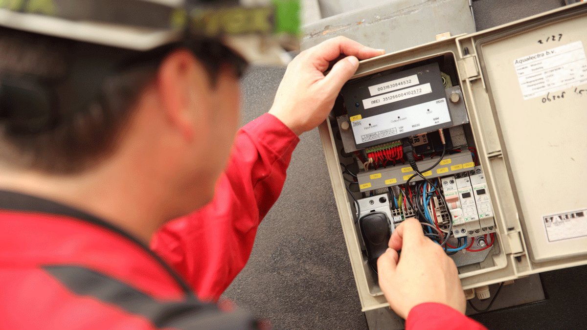 Pompmonteur installeert een storingsmelder bij tijdelijke pompinstallatie, zodat er snel geschakeld kan worden bij storing.