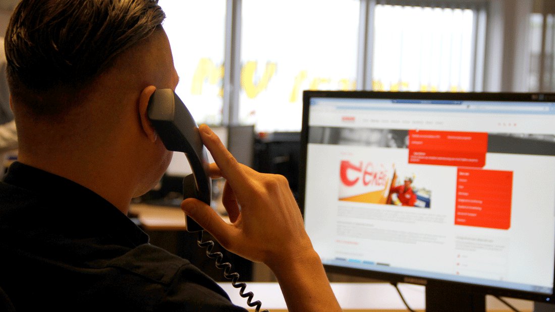 Een medewerker van Eekels Pompen zit achter de computer en heeft telefonisch contact met de klant