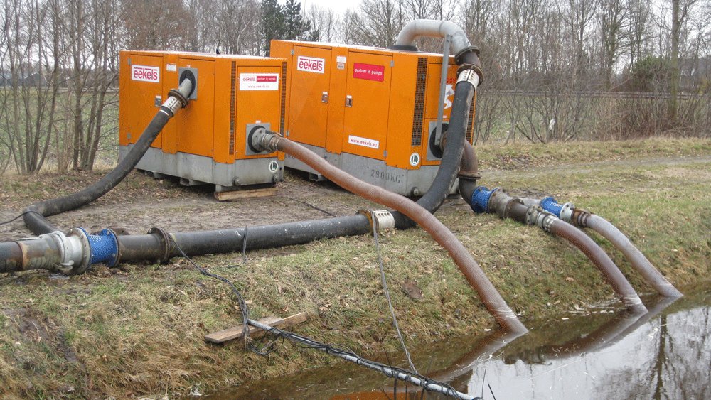 Tijdelijke pompinstallatie met oranje pompen staan langs het water voor het verpompen van slootwater.