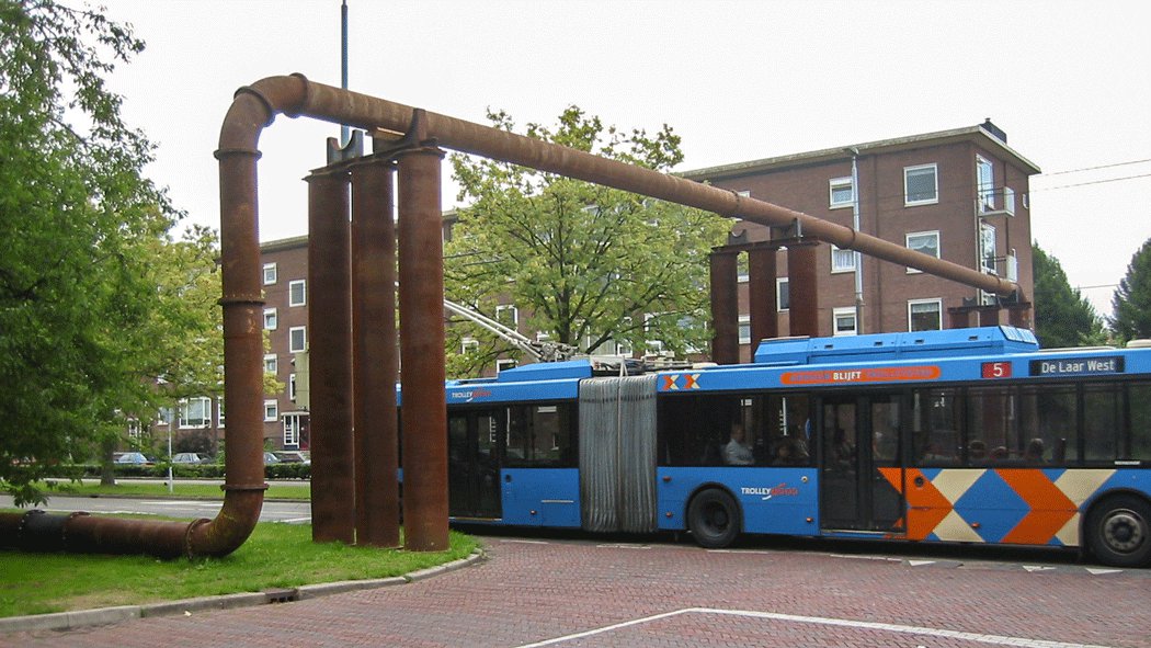 Een blauwe bus rijdt onder een leidingbrug door in de stad